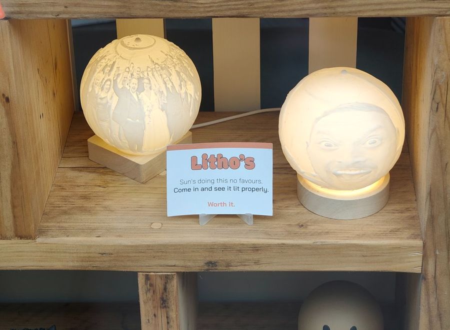 Two glowing lithophane moon lamps on a wooden shelf