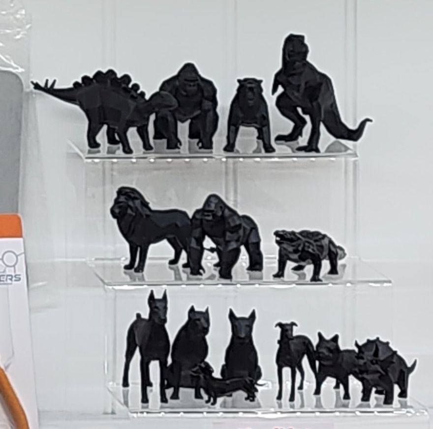 Black low poly dinosaurs, gorillas, big cats and dogs on a stand